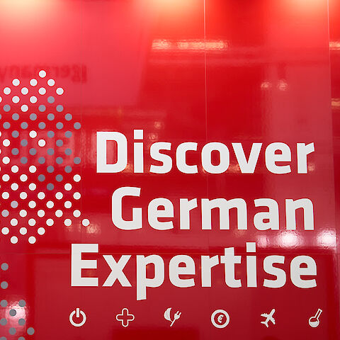 Rote Messewand mit Schriftzug "Discover German Expertise" | © GCB